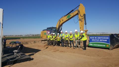 Groundbreaking ceremony with team in neon yellow PPE in front of a bulldozer